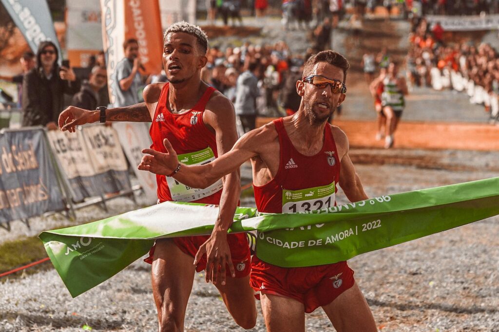 Two male athletes cross the finish line at a marathon, capturing the intense competition.