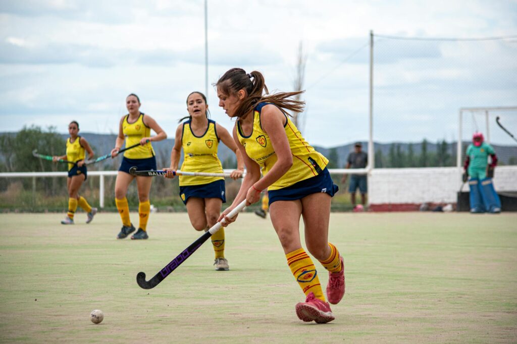 Energetic field hockey game with focused female players on an outdoor field.